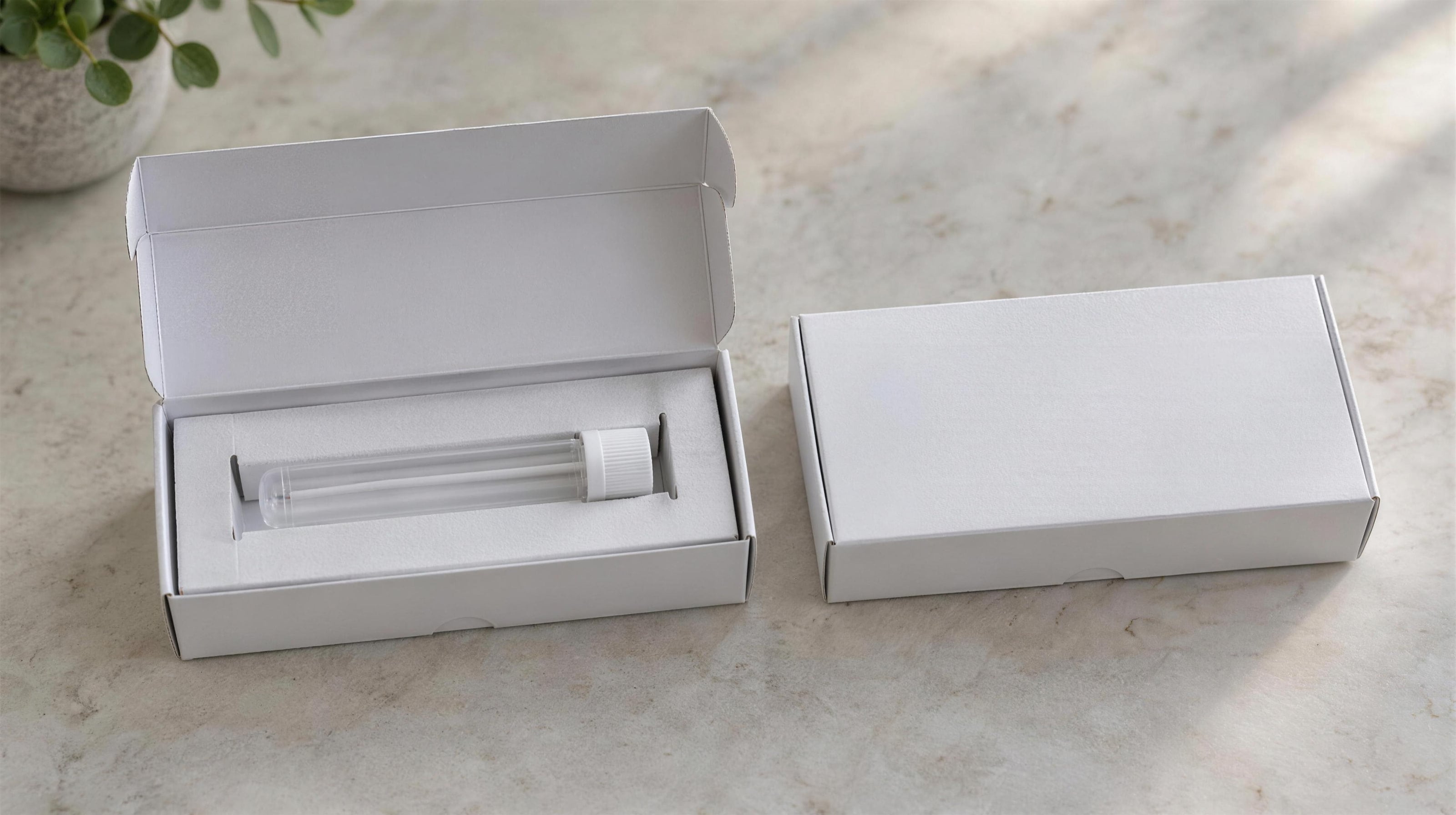 Two plain, unbranded kit boxes, one open with an empty sample tube inside.
