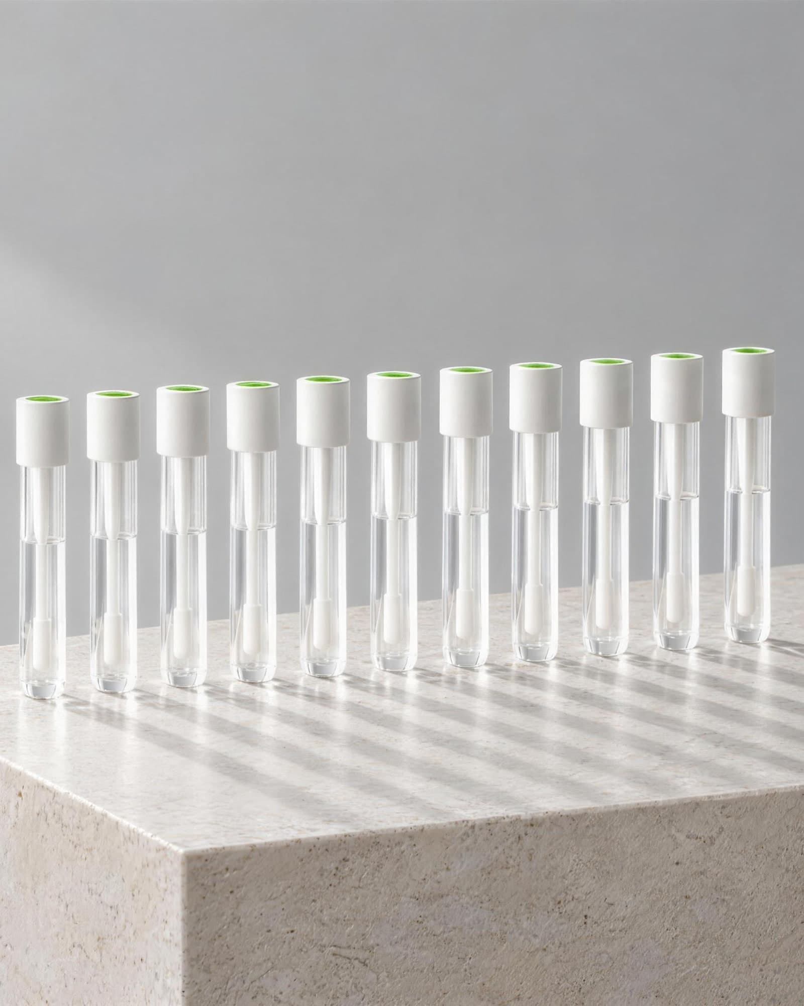 A row of identical white-capped collection tubes standing on a limestone plinth, banded window light falling across a pale wall behind them.