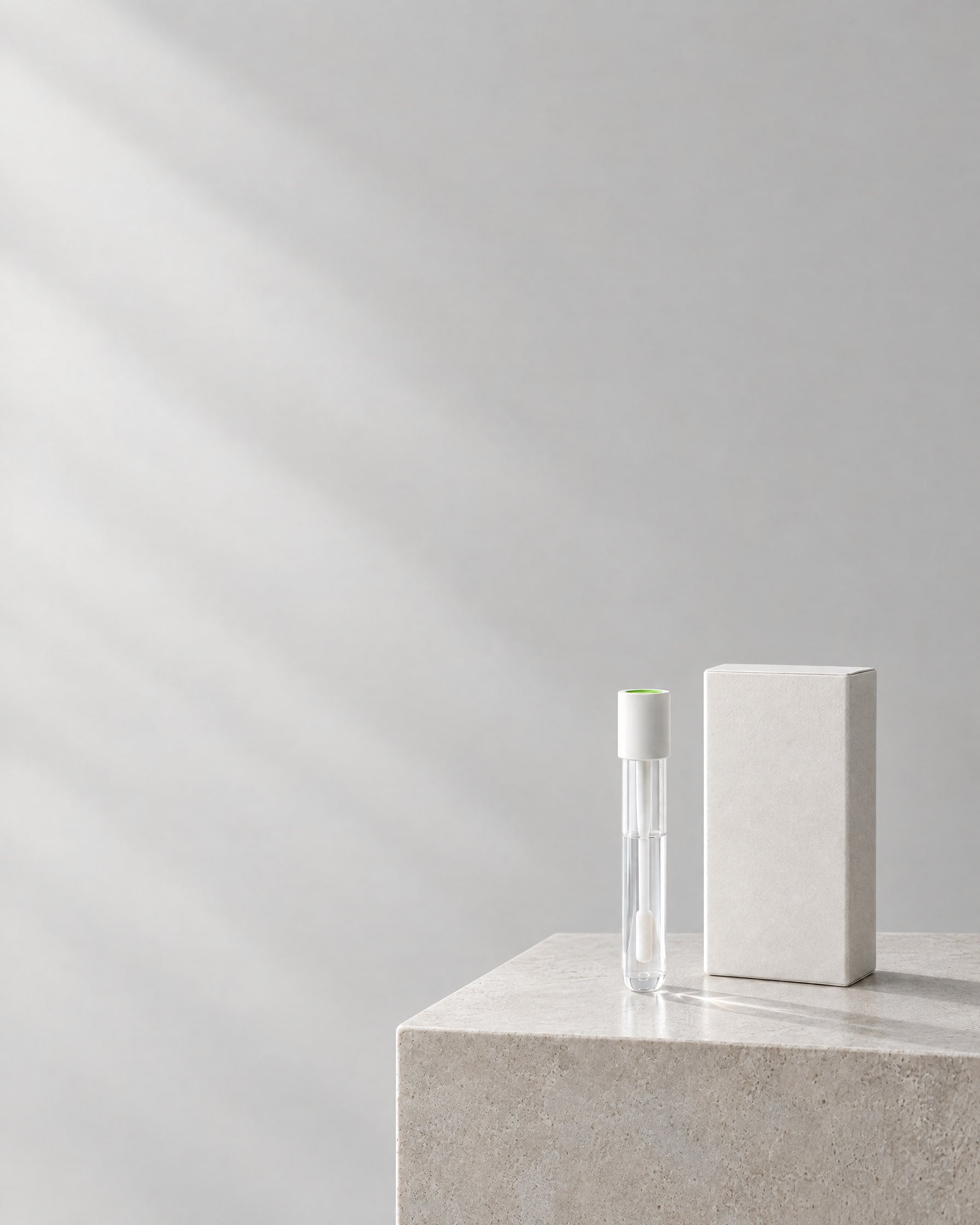 The GeneMatrix saliva collection kit: a sealed collection tube beside its box, on a stone plinth.