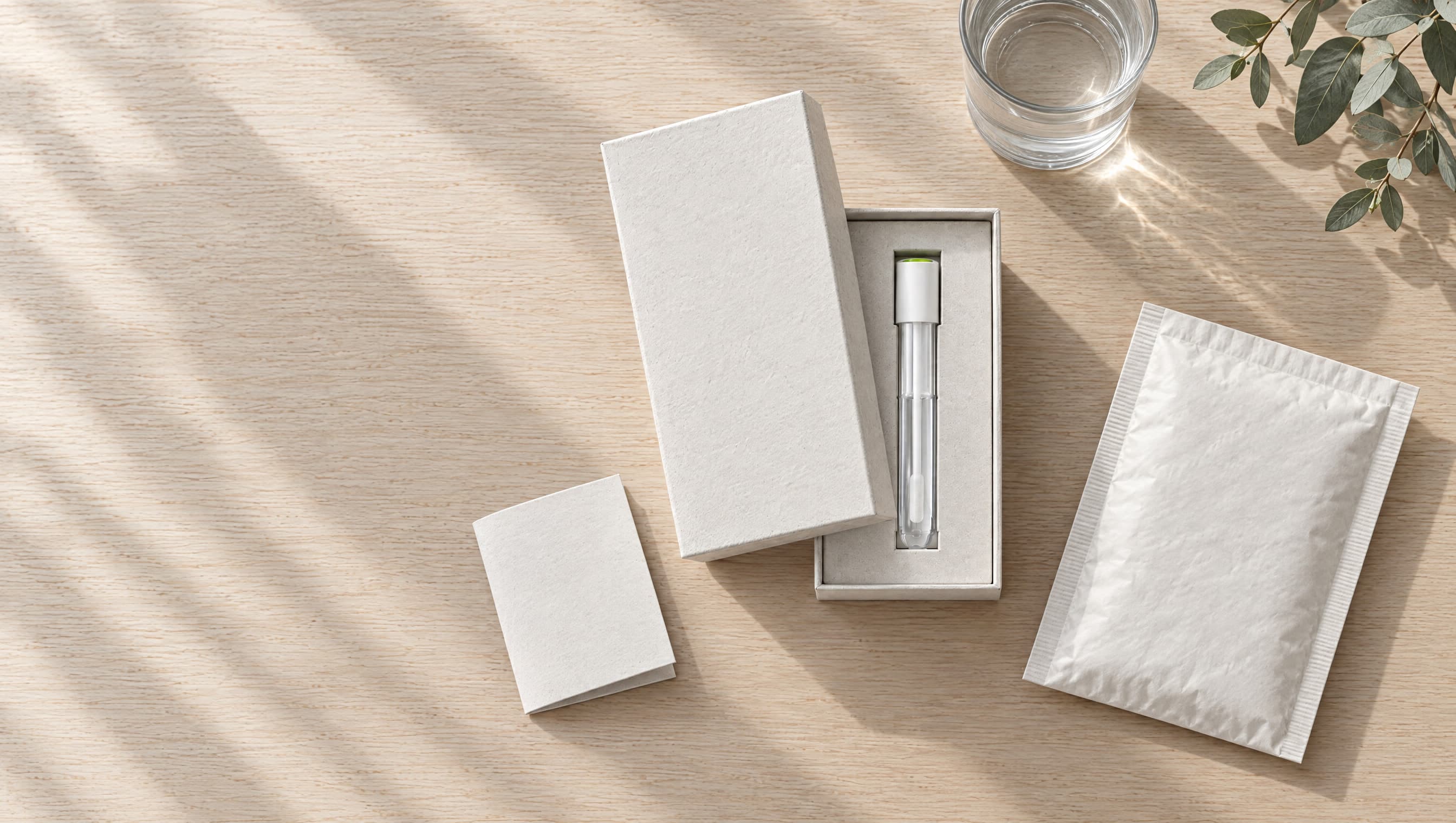 The kit laid out on an oak table: an open box with the collection tube, a small instruction card and a return mailer.